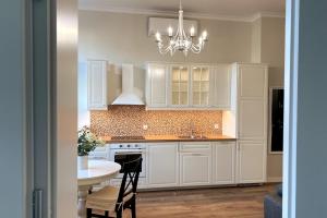 una cucina con armadi bianchi, tavolo e lampadario pendente di Krakowska Street Old Town Apt 16 a Skorka Altre 7 foto