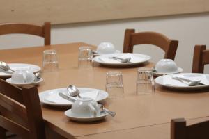 a wooden table with white plates and silverware on it at Rivotorto Retreat House in Birkirkara