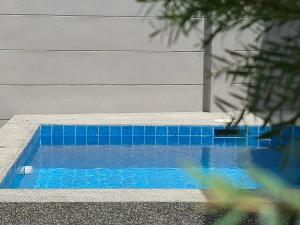 a blue tiled swimming pool next to a building at Bestest Pool Villa in Krabi