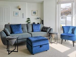 a living room with a couch and blue chairs at Seascape - St Catherine's Court in Fowey