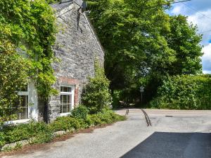 an old stone house with a road in front of it at Hollyhocks Cottage in Helland