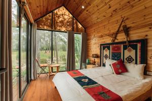 a bedroom with a bed and a large window at Phoenix Mộc Châu Resort in Mộc Châu