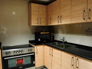 cocina con armarios de madera, fogones y fregadero en Pearl of Abu Dhabi, en Abu Dabi