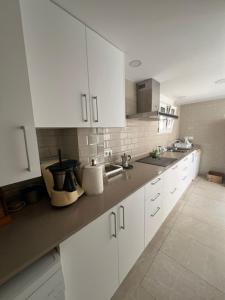 a white kitchen with white cabinets and a sink at Isla Sicilia in Oliva
