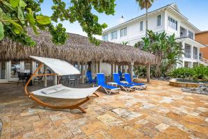 un patio avec des chaises bleues et un bâtiment au toit de chaume dans l'établissement Gulf Front Dreams, à Clearwater Beach