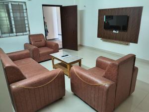 a living room with two chairs and a table and a tv at Tranquill Homestay in Tirupati