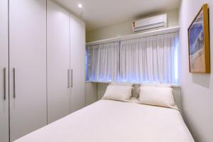 a small bedroom with a bed and a window at Live a dream in the heart of LEBLON in Rio de Janeiro