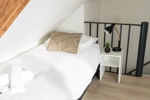 ein Schlafzimmer mit einem weißen Bett und einem Tisch mit einer Lampe in der Unterkunft 6p newly renovated home with unique roof-terrace in Strijp + 52 Fotos