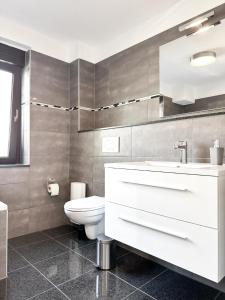 a bathroom with a white sink and a toilet at Beautiful Apartment Köln 15 Min to Phantasialand in Hürth +17 photos