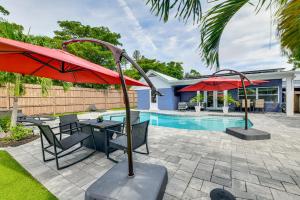 a patio with a table and umbrellas next to a pool at Backyard with Pool and Games! Family Home in Bradenton in Palma Sola Park