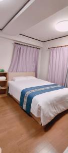 1 dormitorio con 1 cama grande y cortinas moradas en Sea Bloom Hotel, en Dejimamachi