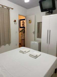 a room with a white bed with a tv on top at Pousada Linda Borboleta in Conservatória