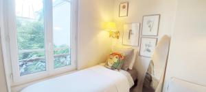 a white room with a bed and a window at PARIS AUTHENTIC HOUSE Small, bright and calm studio in Paris