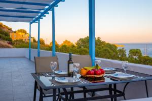 ein Tisch mit einer Schale Obst und einer Flasche Wein in der Unterkunft Monopetra View Leros in Vromolithos