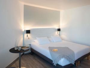 une chambre avec un lit blanc et une table dans l'établissement Novotel La Grande Motte Golf, à La Grande Motte 156 autres photos