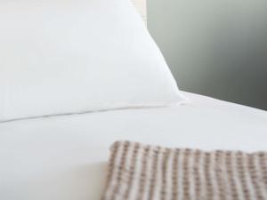 a close up of a white bed with a pillow at Novotel La Grande Motte Golf in La Grande-Motte