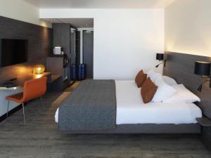 a hotel room with a large bed and a desk at Novotel La Grande Motte Golf in La Grande-Motte
