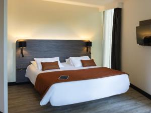 une chambre avec un grand lit avec une grande tête de lit dans l'établissement Novotel La Grande Motte Golf, à La Grande Motte