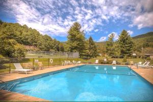 a large blue swimming pool with chairs and tables at Bear Lodge Inn - Banner Elk Peaceful & Cozy Cabin Retreat in Banner Elk