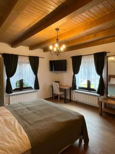 a bedroom with a bed and a desk and two windows at Iedera Bucovinei in Suceviţa