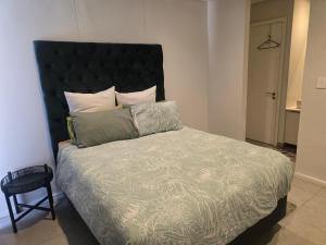 Un dormitorio con una cama grande con cabecero negro. en Isibaya holiday leisure, en Sibaya