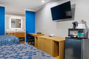 a hotel room with a bed and a tv on the wall at Signature Inn San Jose in San Jose