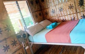 un petit lit dans une chambre avec une fenêtre dans l'établissement Hilltop chalet, with AC, private bathroom, kitchen & balcony with views, à Coron