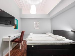 um quarto com uma cama, uma secretária e uma televisão em Mosebacke Hostel em Estocolmo