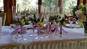 Una mesa con varias copas de vino y flores encima. en Pension Curmatura Stezii, en Răşinari