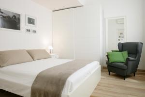 een witte slaapkamer met een bed en een stoel bij The Riverside Suite in Mira