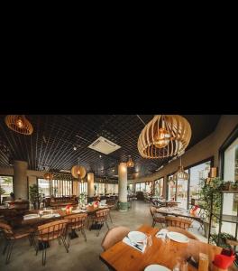 a restaurant with wooden tables and chairs and chandeliers at Caesar Resort Spa Long Beach 
