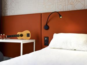 a guitar on a wall next to a bed at ibis Rodez Centre in Rodez +96 photos