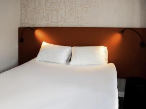 a bedroom with a bed with two white pillows at ibis Rodez Centre in Rodez