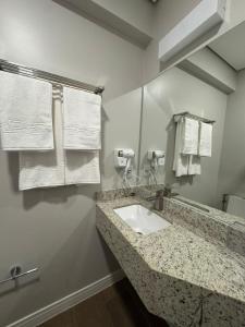 a bathroom with a sink and a mirror and towels at Hotel C jaguariuna in Jaguariúna +2 photos