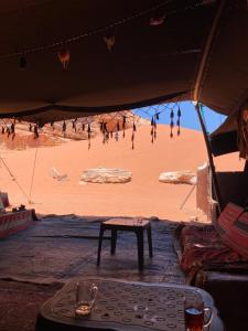 a tent with a table and people on the beach at Sahara Camp Wadi Rum in Wadi Rum