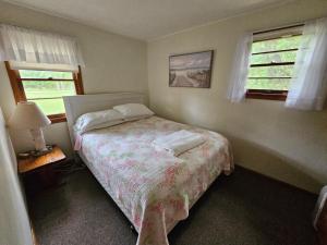a small bedroom with a bed and two windows at Brookhaven 4 in Maple City