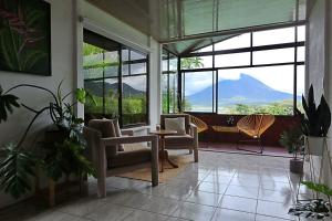 un salon avec des chaises, une table et des fenêtres dans l'établissement Volcano & Lake Arenal View Suite with Soaking tub, à La Fortuna