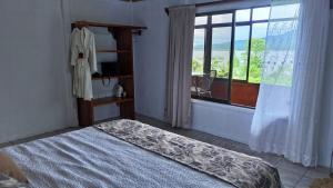 une chambre avec un lit et une fenêtre avec une chaise dans l'établissement Volcano & Lake Arenal View Suite with Soaking tub, à La Fortuna