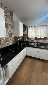 a kitchen with white cabinets and black counter tops at Casa ampla próxima à Rua do Lazer in Santa Teresa