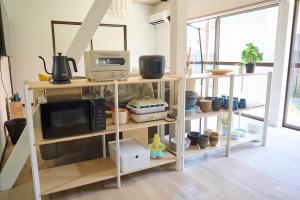 a kitchen with wooden shelves with a microwave and a microwave at IZUMI HOUSE - 成田空港から車で22分 - 最大8名 - 駐車場2台完備 - Switch有 - 10月28日以降ペット歓迎 in Yachimata