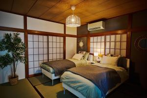 a bedroom with two beds and a potted plant at IZUMI HOUSE - 成田空港から車で22分 - 最大8名 - 駐車場2台完備 - Switch有 - 10月28日以降ペット歓迎 in Yachimata