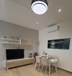 un salon avec une télévision, une table et des chaises dans l'établissement Apartamentos Luz de Luna B, à Churriana de la Vega