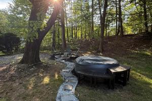 a hot tub sitting next to a tree in the woods at Luxury RV - Hot Tub - Fire Pit - Outdoor Serenity in Blue Ridge