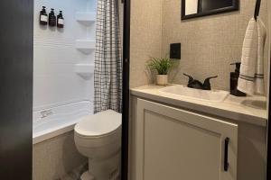 a bathroom with a white toilet and a sink at Luxury RV - Hot Tub - Fire Pit - Outdoor Serenity in Blue Ridge