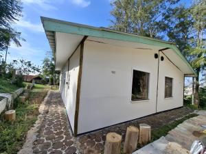 a small white building with a green roof at Chalés do Rizzo 2 in Cotia