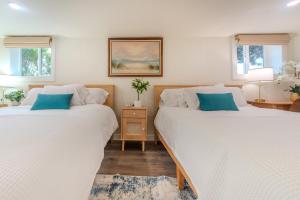 Cette chambre comprend 2 lits avec des draps blancs et des oreillers bleus. dans l'établissement Bremerton Waterfront Views, à Bremerton
