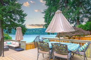 une terrasse en bois avec une table, des chaises et un parasol dans l'établissement Bremerton Waterfront Views, à Bremerton