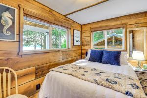 a bed in a room with wooden walls and windows at Outdoor Kitchen and Canal Views Cabin in Quilcene! in Seabeck