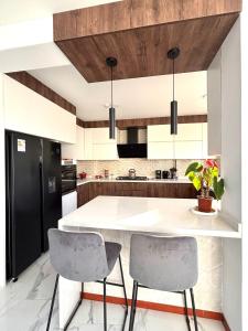 a kitchen with a white counter and two chairs at Arequipa 360 in Paucarpata +7 photos