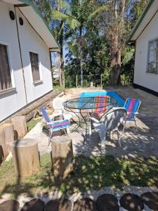 a patio with a table and chairs and trees at Chalés do Rizzo 2 in Cotia +5 photos